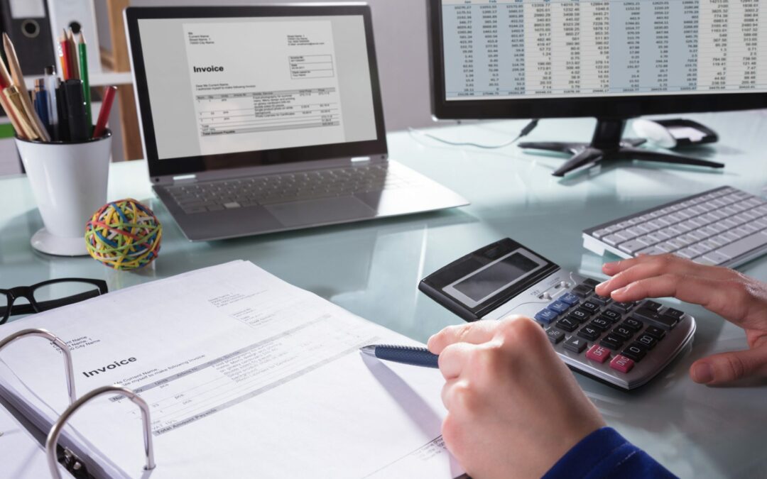 business woman at desk with calculator viewing invoices