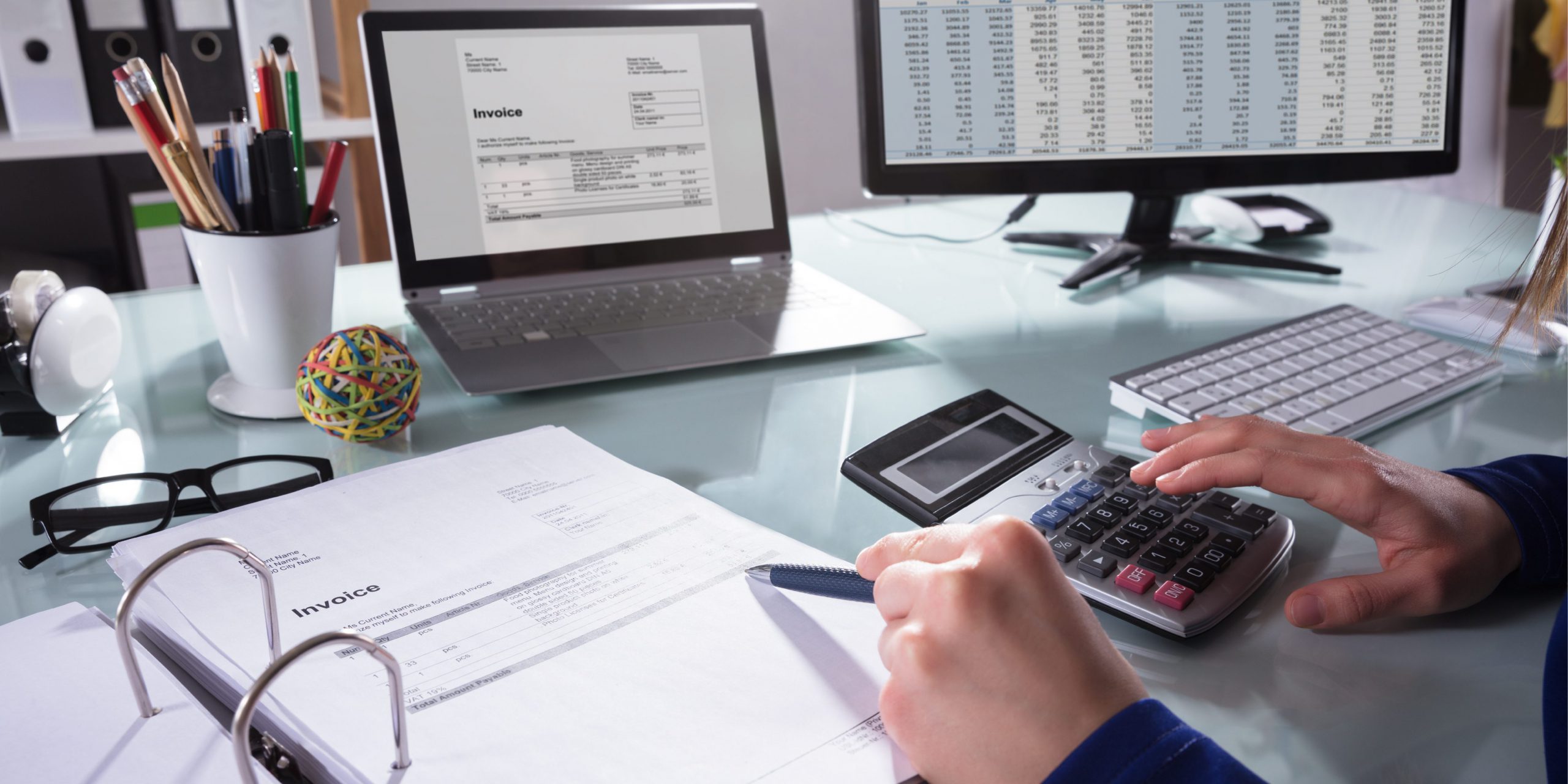 business woman at desk with calculator viewing invoices