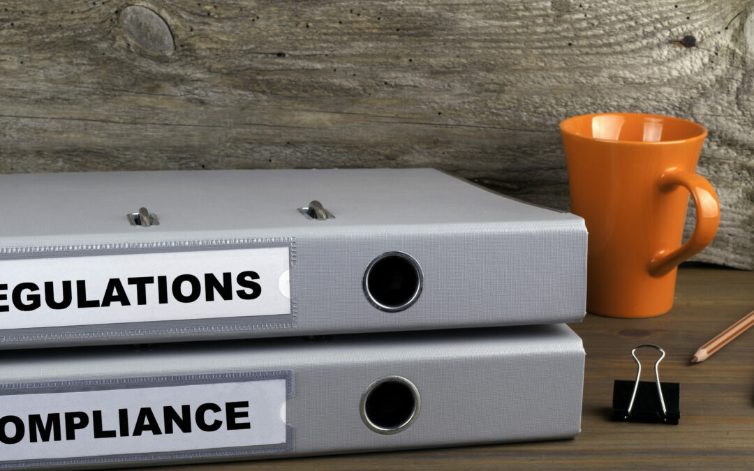 desk with regulations and compliance binders next to office supplies