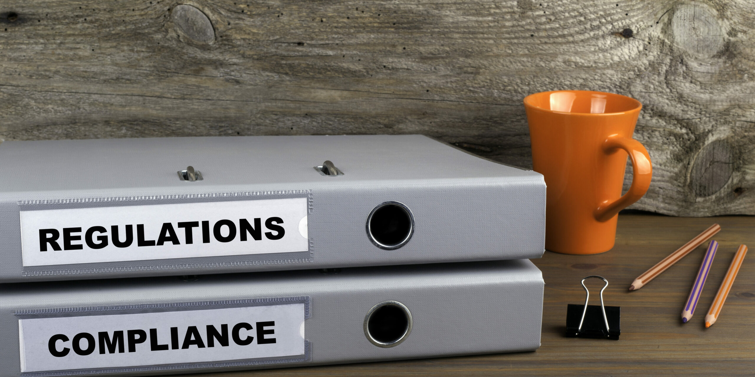 desk with regulations and compliance binders next to office supplies