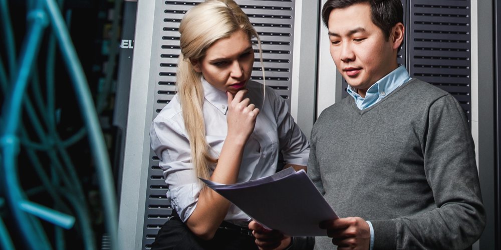 man and woman in server room looking at documents