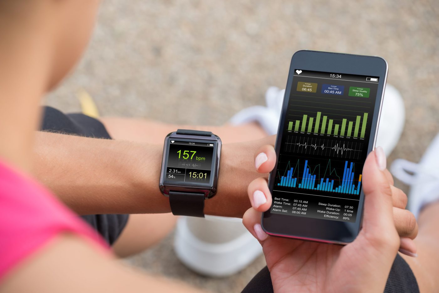 Female runner looking at her mobile and smart watch heart rate.